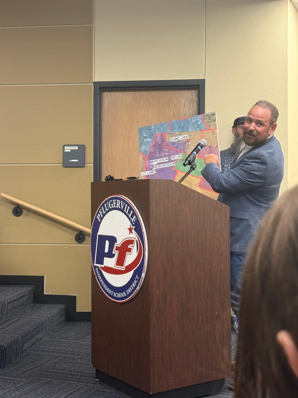 A community member speaks at the PfISD podium beside a proposed boundary map.